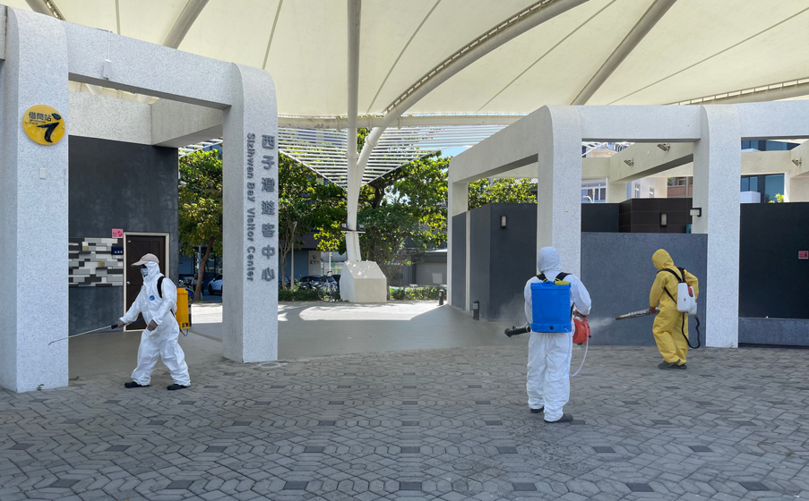 工作團隊在公共建築入口進行環境消毒