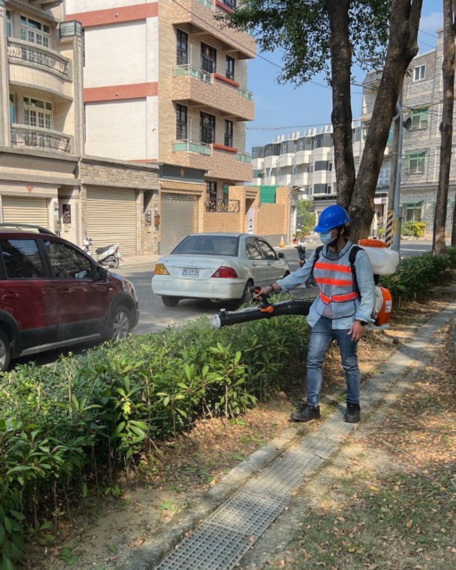 工作人員使用背負式設備沿道路綠帶噴灑